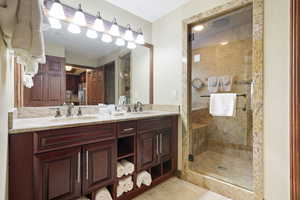 Bathroom featuring double vanity, a stall shower, and tile patterned floors