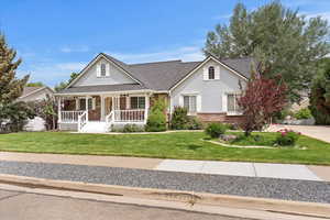 View of front of home with brick siding, covered porch, and a front lawn