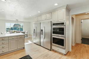 Kitchen with appliances with stainless steel finishes, light wood finished floors, recessed lighting, light countertops, and hanging light fixtures