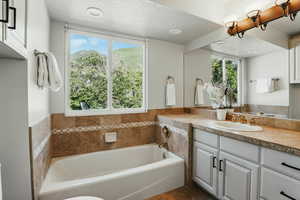 Bathroom with vanity, a garden tub, and a textured ceiling