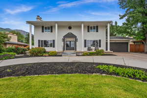 Neoclassical / greek revival house featuring a chimney, concrete driveway, an attached garage, french doors, and a mountain view
