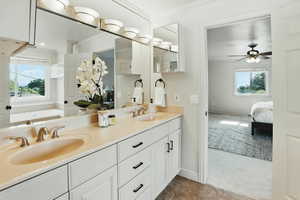 Bathroom featuring ornamental molding, double vanity, ensuite bath, baseboards, and a ceiling fan