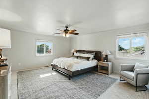 Bedroom featuring light colored carpet, crown molding, baseboards, and a ceiling fan