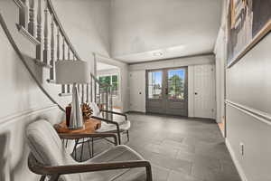 Entrance foyer featuring stairs, a high ceiling, baseboards, and tile patterned floors