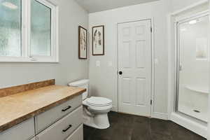 Bathroom with tile patterned flooring, vanity, toilet, and a stall shower