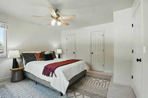 Carpeted bedroom featuring baseboards, ceiling fan, and multiple closets