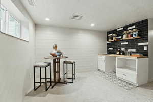Bar area with a textured ceiling, light carpet, and recessed lighting