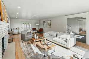 Living room with a fireplace, light wood finished floors, recessed lighting, and stairway