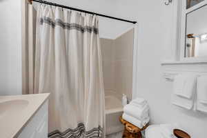 Bathroom with toilet, shower / bathtub combination with curtain, and vanity