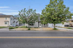 View of property hidden behind natural elements featuring concrete driveway, a mountain view, roof with shingles, and a residential view