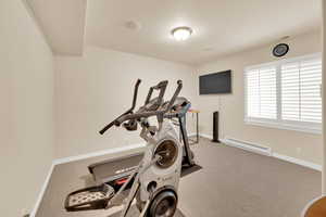 Workout room with baseboard heating, carpet, and baseboards