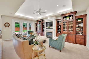 Living area featuring a raised ceiling, fireplace, and recessed lighting