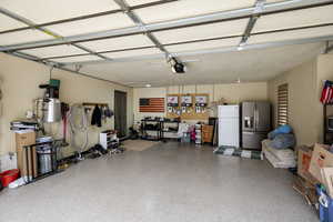 Garage with stainless steel fridge, freestanding refrigerator, a garage door opener, and a central vacuum unit