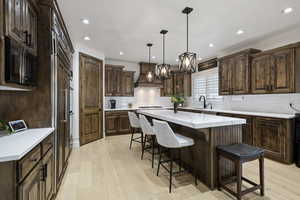 Kitchen with a sink, black microwave, a center island, light wood-style flooring, and a kitchen bar