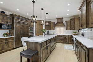 Kitchen featuring custom range hood, a warming drawer, stainless steel appliances, light wood finished floors, and recessed lighting