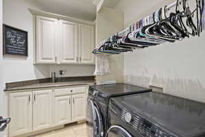 Washroom featuring washer and dryer, cabinet space, and light tile patterned flooring