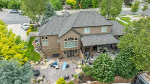 Rear view of property with stucco siding, roof with shingles, french doors, a patio area, and stone siding