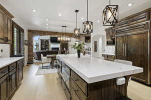 Kitchen with stainless steel microwave, paneled built in refrigerator, recessed lighting, light wood-style floors, and arched walkways