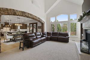 Living room with high vaulted ceiling, light carpet, a chandelier, recessed lighting, and a fireplace