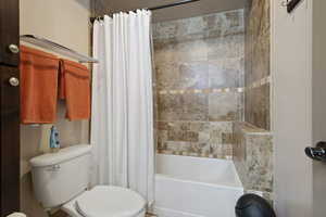 Full bath featuring toilet and shower / tub combo with curtain