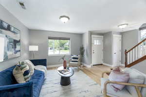 Living area featuring healthy amount of natural light, wood finished floors, baseboards, stairs, and a textured ceiling