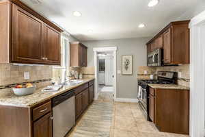 Kitchen featuring appliances with stainless steel finishes, a sink, tasteful backsplash, washer / dryer, and recessed lighting