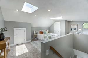 Bedroom with a skylight, vaulted ceiling, light colored carpet, baseboards, and recessed lighting