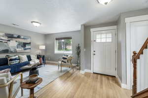 Entryway featuring healthy amount of natural light, baseboards, light wood finished floors, and a textured ceiling