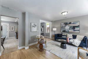 Living room with light wood finished floors, a textured ceiling, and baseboards