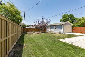 View of yard featuring an outdoor structure, a garden, concrete driveway, and a detached garage
