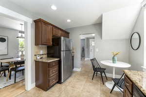 Kitchen featuring freestanding refrigerator, tasteful backsplash, light stone counters, baseboards, and recessed lighting