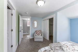 Bedroom with carpet flooring, a closet, a textured ceiling, and baseboards