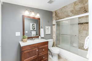 Bathroom featuring vanity, toilet, bath / shower combo with glass door, and tile patterned floors