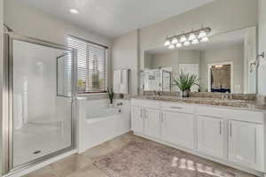 Full bathroom featuring a stall shower, double vanity, a garden tub, and tile patterned flooring