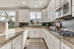 Kitchen with stainless steel appliances, dark wood finished floors, white cabinets, recessed lighting, and a mountain view