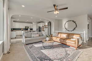 Living room with arched walkways, a ceiling fan, recessed lighting, and baseboards