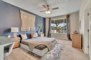 Bedroom featuring carpet flooring, a textured ceiling, baseboards, and ceiling fan