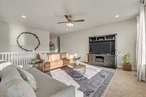 Living area with arched walkways, ceiling fan, light carpet, recessed lighting, and baseboards