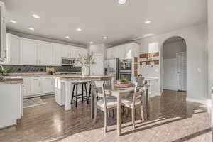 Dining space featuring arched walkways, light wood finished floors, recessed lighting, and baseboards