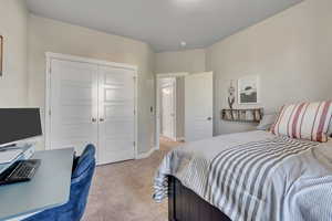 Bedroom with light colored carpet, a closet, and baseboards