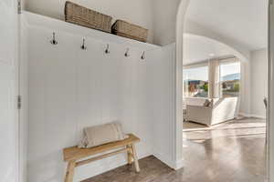Mudroom with arched walkways, baseboards, and wood finished floors