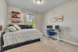 Carpeted bedroom with baseboards, a textured ceiling, and an office area