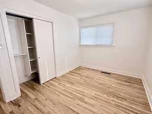 Unfurnished bedroom with light wood-type flooring, baseboards, and a closet