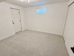 Unfurnished room featuring light carpet and baseboards