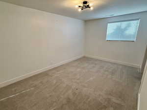 Unfurnished room featuring light carpet and baseboards
