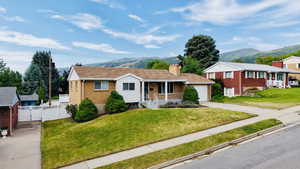 Single story home with a porch, a mountain view, concrete driveway, brick siding, and a gate