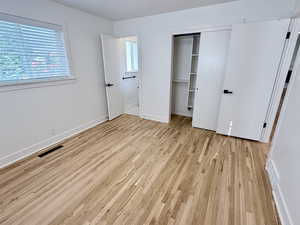 Unfurnished bedroom with light wood finished floors, a closet, multiple windows, and baseboards