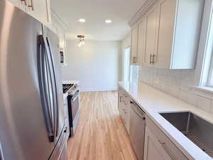 Kitchen featuring stainless steel appliances, light wood finished floors, decorative backsplash, light stone countertops, and recessed lighting