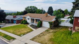 View of front facade featuring driveway, a garage, a chimney, and brick siding
