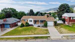 Single story home with covered porch, concrete driveway, a garage, a mountain view, and a chimney